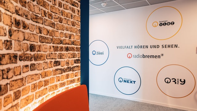 Auf einer Wand steht Vielfalt hören und sehen mit den verschiedenen Logos von Radio Bremen